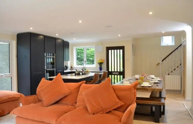 Open-plan lounge and kitchen with orange sofas